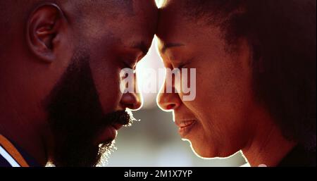 Coppia africana in occhi d'amore chiuso appoggiandosi sulla fronte insieme all'esterno con lente-flare, buono per la transizione Foto Stock
