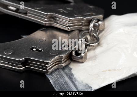 Manette con farmaci in una borsa su sfondo nero primo piano. Legge. Un crimine Foto Stock