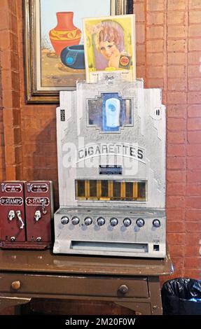 Distributore automatico di sigarette da tavolo antico accanto alle macchine per francobolli vintage. Foto Stock