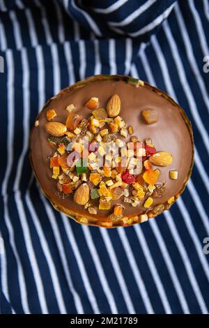 Una torta pasquale decorata con frutta candita si erge su un grembiule blu a strisce. Pasqua religiosa vacanza concetto Foto Stock