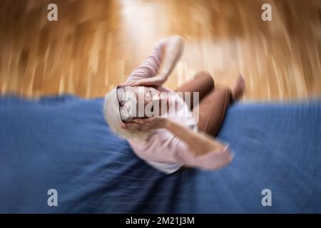 Donna anziana affetta da mal di testa che riposa a casa sul divano Foto Stock