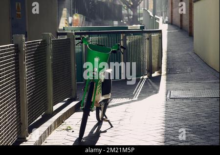 Londra UK : 10 Dic 2022 - bicicletta Lime-e in posizione verticale su un vicolo pedonale urbano in una giornata di sole brillante in inverno Foto Stock