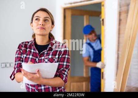 Donna che compila documenti in appartamento durante i lavori di ristrutturazione Foto Stock