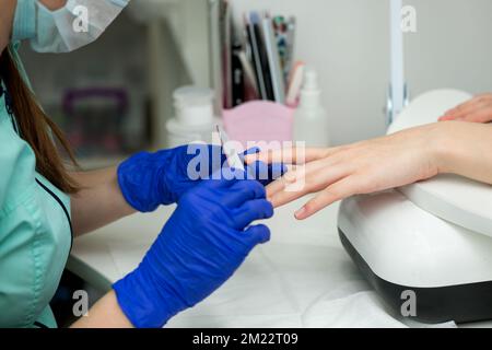 Donna mani in un salone delle unghie che riceve una manicure classica - riempimento unghie. Cura delle unghie. Procedure di manicure e pedicure e SPA. Primo piano, selettivo Foto Stock