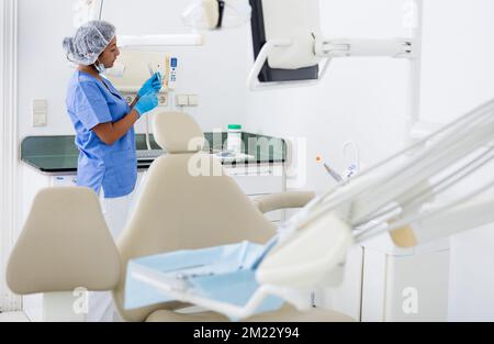 Dentista femminile che controlla e dispone gli attrezzi in ufficio dentale Foto Stock