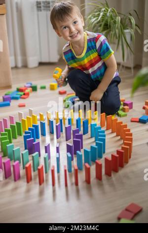 Carino maschio capretto costruzione legno edificio colorato cubo blocco Montessori materiale giocare a casa Foto Stock