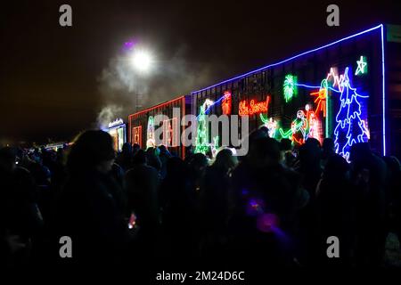 La gente guarda l'arrivo del treno canadese Pacifico ora di Natale, l'illuminazione al neon sulle vetture del treno. Il Train organizza un concerto di beneficenza per vari tipi di carattere Foto Stock