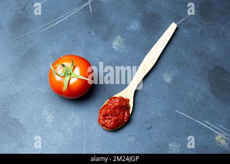 Concentrato di pomodoro, concentrato di pomodoro su cucchiaio di legno, vista dall'alto. Foto Stock