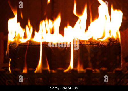 Un primo piano di un legno in fiamme si acciglia in un firepit metallico di un camino Foto Stock