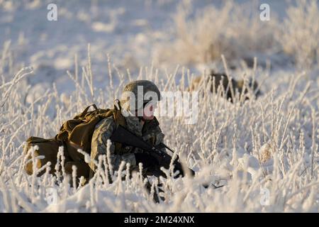 2 dicembre 2022 - Joint base Elmendorf-Richardson, Alaska, Stati Uniti - Un cadetto ROTC dell'esercito dell'Alaska prende una posizione difensiva dopo lo scarico da un elicottero Black Hawk dell'esercito dell'Alaska UH-60L assegnato al 1-207th Aviation Regiment durante un evento di addestramento di assalto aereo alla Joint base Elmendorf-Richardson, Alaska, Dicembre. 2. Il distaccamento del Seawolf ROTC si è manovrato su più di un miglio di terreno ghiacciato per attaccare le forze di opposizione e per assicurarsi il suo obiettivo. Il battaglione dell'aviazione generale di supporto della Guardia nazionale dell'Alaska si allena regolarmente con tutte le filiali del mil Foto Stock