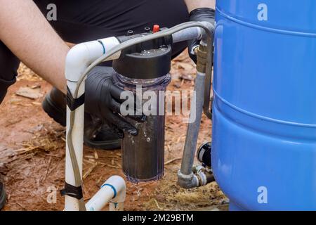 Sostituire i filtri sostituibili per la pulizia dell'acqua vicino a casa da parte di operatori professionali che eseguono lavori di manutenzione sostituendo i filtri sostituibili all'esterno della casa Foto Stock