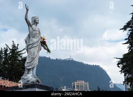 Una vista della statua di Gesù Cristo risorto con fiori nelle sue mani nel Central Centery situato in centro con grattacieli e Monserrate Chiesa a. Foto Stock