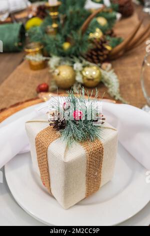 Rustico natale servito tavolo. Bella tavola impostazione con decorazioni natalizie in soggiorno. Cena di Natale, design festa, concetto - tavolo sett Foto Stock