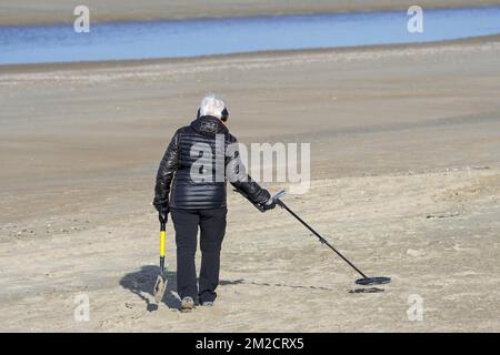 Donna anziana con metal detector beachcombing sulla spiaggia di sabbia lungo la costa del Mare del Nord in inverno | Femme agée, pilleur d'épaves armée de détecteur de métaux sur la plage de la Côte Belge 30/01/2018 Foto Stock