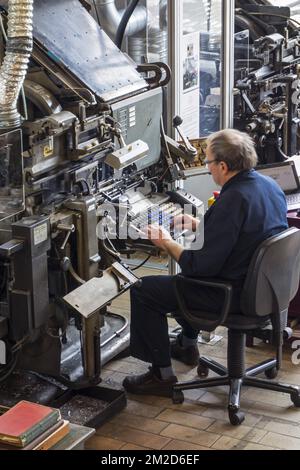 Linotype machine operator enters text on a 90-character keyboard at printing business | Compositeur travaille avec Linotype, machine de composition au plomb qui utilise un clavier alphanumérique à 90 caractères 11/02/2018 Stock Photo