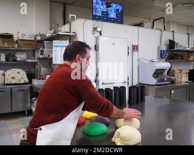 cuoco di baker che fa rosso giallo violetto e verde piccoli 30 grammi di panini colorati per l'evento finger food - preparazione catering Foto Stock