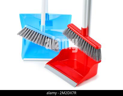 Dustpans con scope su sfondo bianco, primo piano Foto Stock