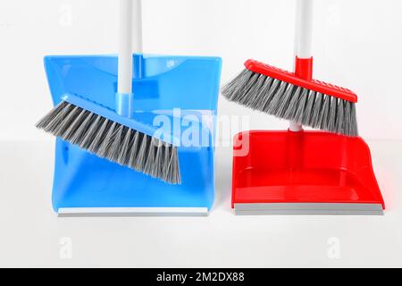 Dustpans con scope su sfondo bianco, primo piano Foto Stock
