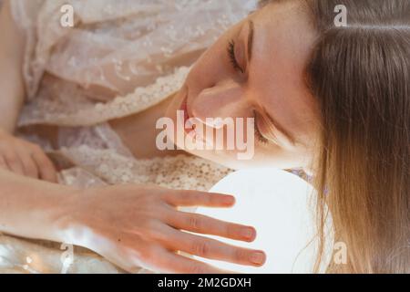 Primo piano donna addormentata con la testa sulla sfera luminosa immagine ritratto Foto Stock