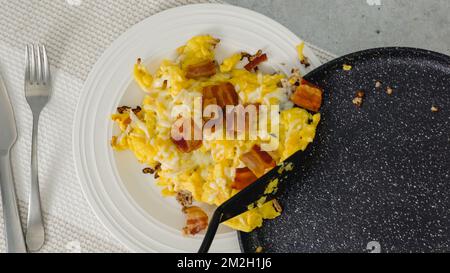 Serve la colazione. Uova strapazzate fritte con formaggio e pancetta. Vista ravvicinata dall'alto Foto Stock