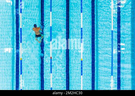 A bird's eye view of a man swimming alone in a swimming pool. High quality photo Stock Photo