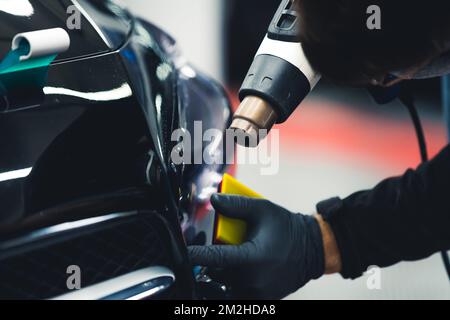 Processo di dettaglio auto - tintura di lampade per auto effettuata da un esperto in guanti protettivi con l'uso di attrezzature professionali. . Foto di alta qualità