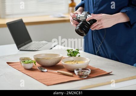 Primo piano del fotografo che fa un ritratto ravvicinato della zuppa in ciotole con la fotocamera digitale Foto Stock