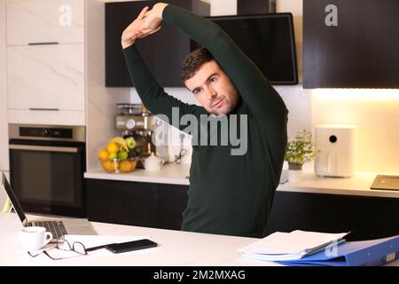 Uomo che si allunga in ufficio domestico Foto Stock