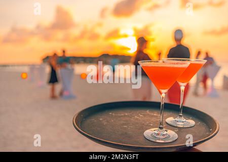 Due cocktail con spiaggia sfocata e cielo colorato al tramonto sullo sfondo. Stile di vita all'aperto di lusso, atmosfera rilassante e romantica Foto Stock