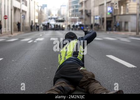 L'illustrazione mostra un protestore che si è posato sulla strada e un sacco di forze di polizia sul retro della strada per una protesta dei giubbotti gialli (Gilets jaunes - gele hesjes) contro l'aumento dei prezzi del carburante e del petrolio, nel centro di Bruxelles, sabato 15 dicembre 2018. BELGA FOTO HATIM KAGHAT Foto Stock