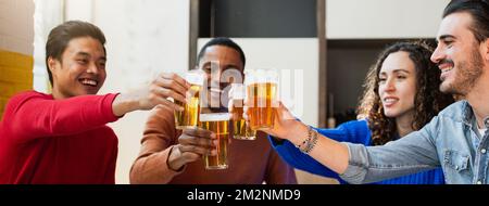 Banner orizzontale o intestazione Gruppo di quattro amici multietnici che mangiano pizza in un ristorante brindando e allietando con bicchieri di birra. Foto Stock