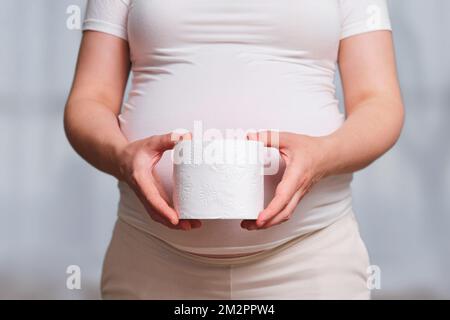 Carta igienica nelle mani di una donna incinta, salotto di casa Foto Stock