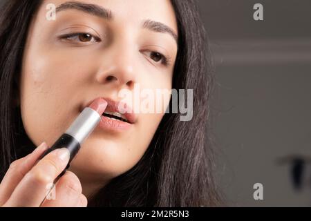Immagine ravvicinata della donna che tiene il rossetto. Ruging balsamo labbro. Aprire delicatamente la bocca. Ragazza caucasica che fa il suo proprio make up. Lifestyle, donna millenaria. Foto Stock