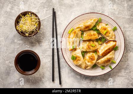 Gyoza, gnocchi fritti in padella giapponese, su sfondo chiaro. Foto Stock