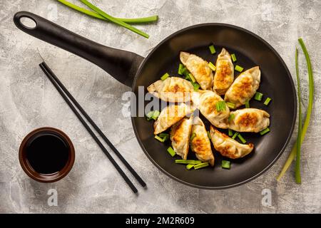 Gyoza, gnocchi fritti in padella giapponese, su sfondo chiaro. Foto Stock