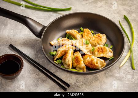 Gyoza, gnocchi fritti in padella giapponese, su sfondo chiaro. Foto Stock