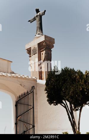 A statue of Jesus on top of a building next to a tree Stock Photo