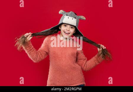 un bambino felice indossa un maglione e un cappello con risvolto in studio. moda invernale per bambini adolescenti. Foto Stock