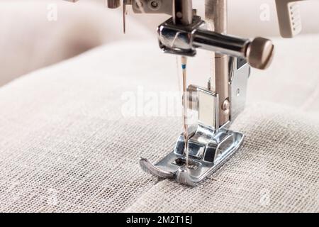 Primo piano di una moderna macchina da cucire, piedino premiatore e capo di abbigliamento da cucire ad aghi. Foto Stock
