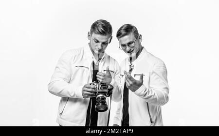 gli uomini gemelli dei fratelli osservano allo stesso modo usano la macchina fotografica vintage, fotografando Foto Stock