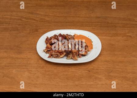 Una tipica tapa da bar spagnoli con orecchie grigliate con salsa per l'immersione Foto Stock