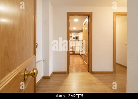 Ingresso di una casa residenziale urbana con carpenteria in rovere su porte, stipiti, battiscopa e pavimenti in laminato Foto Stock