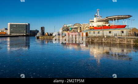 Leith, Edimburgo, Scozia, Regno Unito, 14th dicembre 2022. UK Weather: Acqua del fiume Leith congelata: Le persistenti condizioni di congelamento hanno causato il congelamento del bacino portuale con una nave di fornitura Technip riflessa nel ghiaccio. Credit: Sally Anderson/Alamy Live News Foto Stock