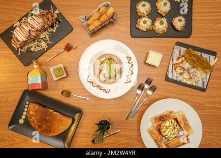 Deliziose ricette venezuelane con cachapa farcita, pataconi assortiti, arepas con formaggio, tequeños allo spuntino e tostadas con salse Foto Stock