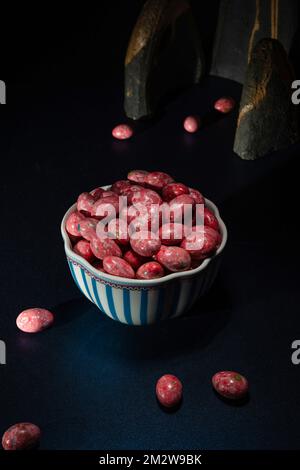 Draghi di cioccolato in glassa colorata croccante. Drago con mandorle in vaso. Caramelle colorate sul tavolo Foto Stock