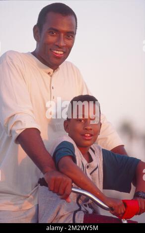 Padre e figlio afroamericano si fermino mentre imparano a guidare una bicicletta per un ritratto Foto Stock