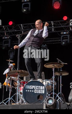 Il batterista della rock band Inspector Cluzo in piedi sul suo basso tamburo per ballare Foto Stock