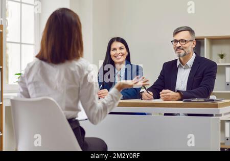 I responsabili delle risorse umane ascoltano un candidato mentre sono seduti alla scrivania durante un colloquio di lavoro Foto Stock