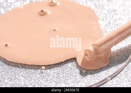 Campione beige a trama di fondazione. Crema con brillantezza d'argento e pipetta. Prodotto per la cura della pelle del viso. Essenza di olio liquida. Splash di collagene di vitamina di bellezza. Cura organica del corpo. Protezione solare Foto Stock