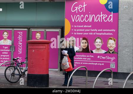 Slough, Berkshire, Regno Unito. 14th dicembre 2022. Una donna pubblica le cartoline di Natale in una casella postale in Slough High Street. I lavoratori della Royal Mail sono stati in sciopero oggi presso l'ufficio di smistamento di Slough in una disputa in corso sulle condizioni salariali e di lavoro. I membri della CWU hanno tenuto un picket ufficiale fuori dall'ufficio di smistamento, tuttavia, i manager e il personale dell'agenzia sono stati portati per continuare a consegnare la posta ai clienti. Credit: Maureen McLean/Alamy Live News Foto Stock